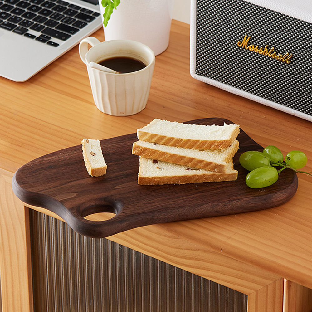 Black walnut snack serving board for bread and grapes on cafe tabletop